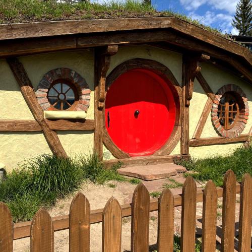 a dog house with a red door and a fence at Едем in Brzezhany