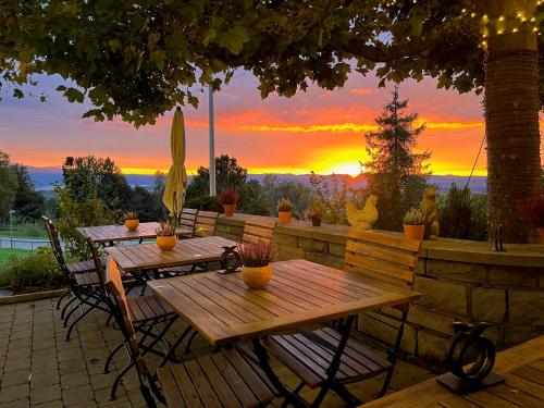 a wooden table and chairs with a sunset in the background at Hotel & Restaurant Hasenstrick in Dürnten