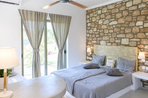 塞奧洛戈斯的住宿－LOGOS Beach Village，一间卧室设有石墙和一张带枕头的床。