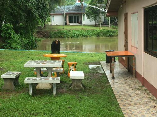 una mesa de picnic y bancos junto a una casa en นาหินลาดรีสอร์ท Nahinlad Resort, en Ban Khok Sawang (2)