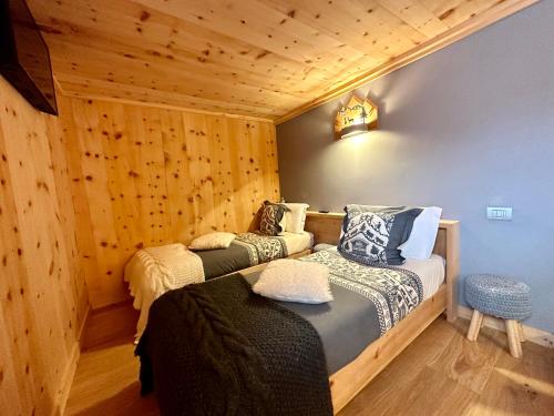 two beds in a room with wooden walls at Al Bait Del Legn 1 in Bormio