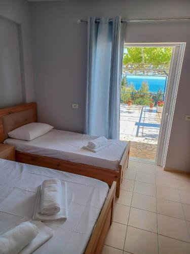 a room with two beds and a large window at Ionian View Guest House in Qeparo