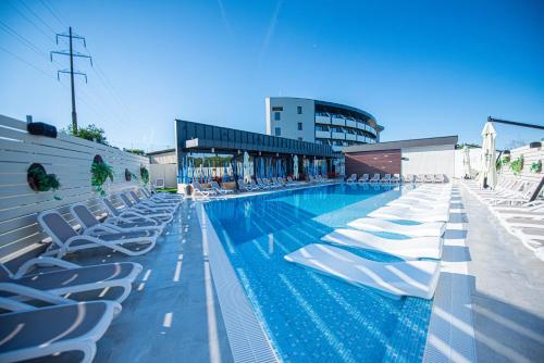 - une piscine avec des chaises longues et des chaises longues dans l'établissement Hotel Aventus, à Băile Felix