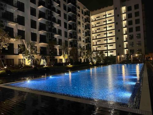 een groot zwembad met blauwe verlichting voor gebouwen bij Armadale Residence Galacity 3 bedroom in Kampong Tabuan