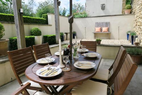 a wooden table with plates and wine glasses on a patio at The Tallet - converted three bed stable - no children under 8 in Yeovil