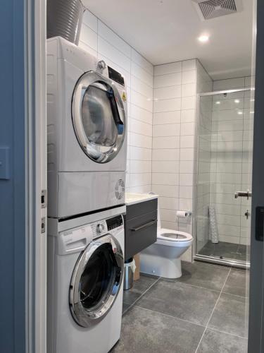 uma casa de banho com 2 máquinas de lavar roupa e um WC em 3 bedroom apartment in Newmarket em Auckland