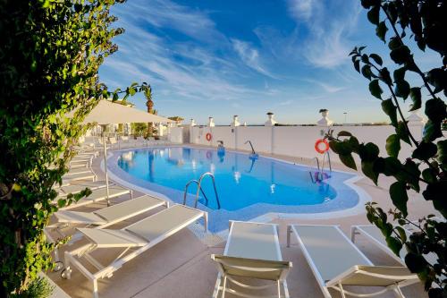 a swimming pool with white lounge chairs next to a building at Gran Sol in Zahara de los Atunes