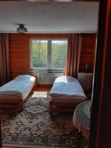 a bedroom with two beds and a window at Zwolaki in Ulanów