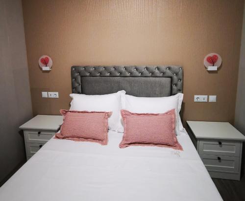 a bedroom with a large bed with two pink pillows at Apartamento MS in Campo Maior