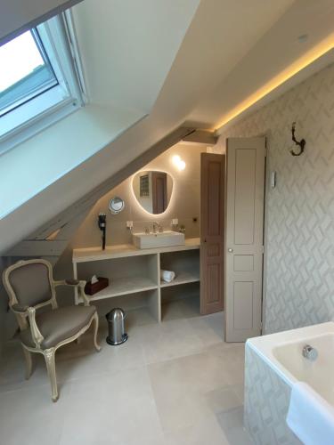 een badkamer met een wastafel en een stoel bij La Petite Lucie in Honfleur