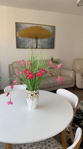 a white table with pink flowers on top of it at Golden Apartament Legionów in Toruń