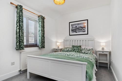 a white bedroom with a bed and a window at Woodfield House - Beautiful Tenby Cottage in Tenby