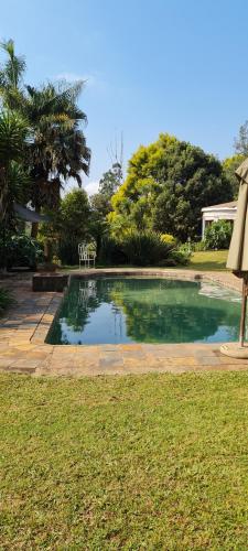 a swimming pool with a table and chairs in a yard at River Suites Sabie in Sabie