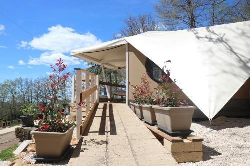 a white tent with potted plants on a sidewalk at Glamping La Ghianda in Elmo