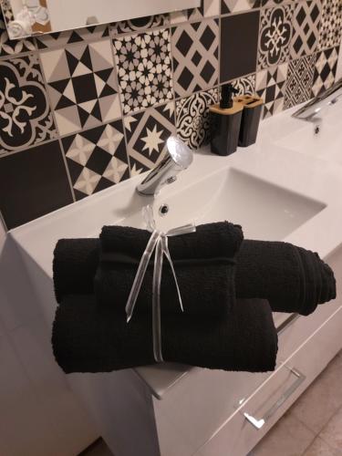 lavabo en el baño con toallas negras en la encimera en petite maison cosy en duplex, en Éguelshardt
