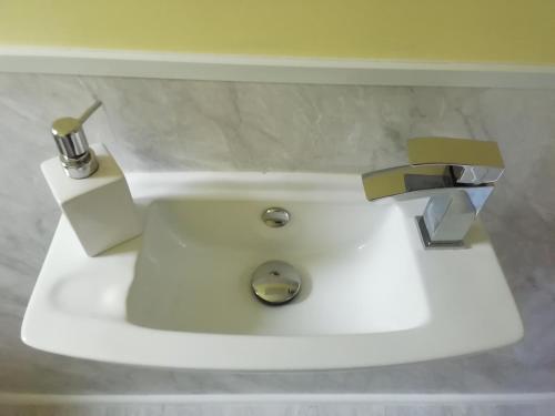 a white sink with two faucets in a bathroom at Wilma's Guest House in Dundonnell