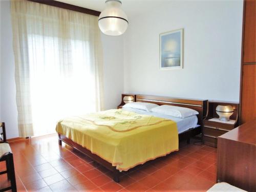 een slaapkamer met een bed met een gele deken bij Spacious apartment in Porto Santa Margherita with shared pool in Porto Santa Margherita di Caorle