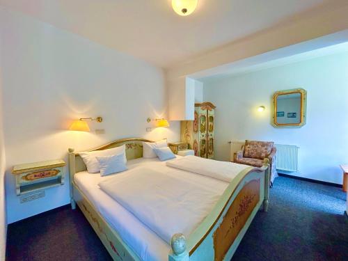 a bedroom with a large bed and a chair at Hotel Bergland in Grainau