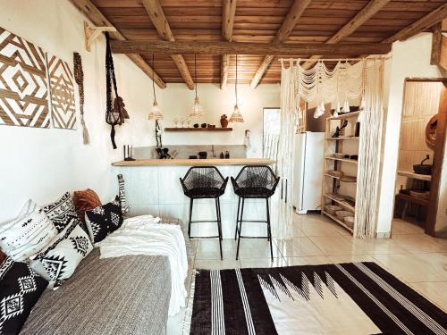 a living room with a couch and a kitchen with stools at CASA MUNDI in Caraíva