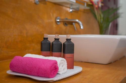 a bathroom counter with three black bottles and a pink towel at Randoni Villa in Raddoluwa