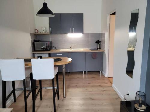 a kitchen with a table and some white chairs at studio privé Centre Saint Louis in Montargis