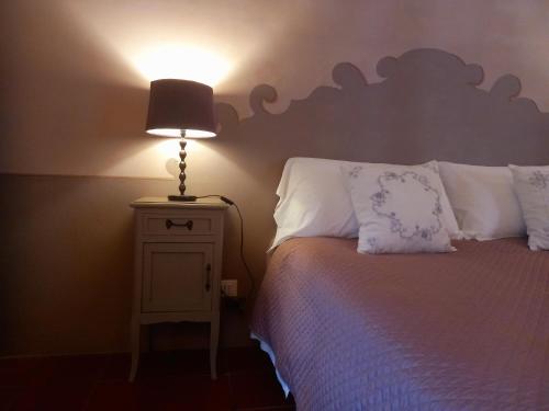a bedroom with a bed with a lamp on a night stand at La Casa Rosa in Pigna
