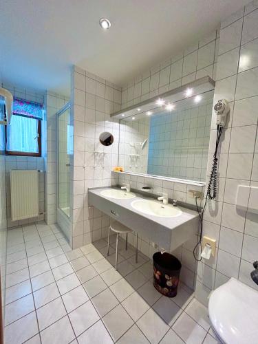 a white bathroom with a sink and a mirror at Hotel Bergland in Grainau
