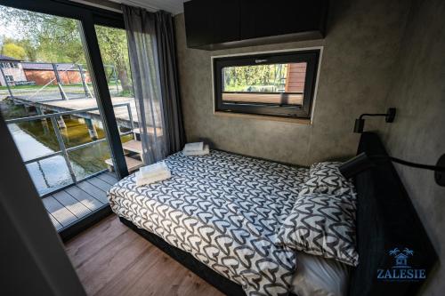 a bedroom with a bed and a large window at Domki na wodzie - Houseboats Zalesie with sauna in Zalesie