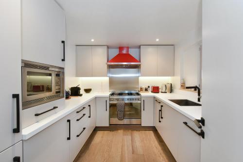 a kitchen with white cabinets and a red hood at London Choice Apartments - Covent Garden - Leicester Square in London