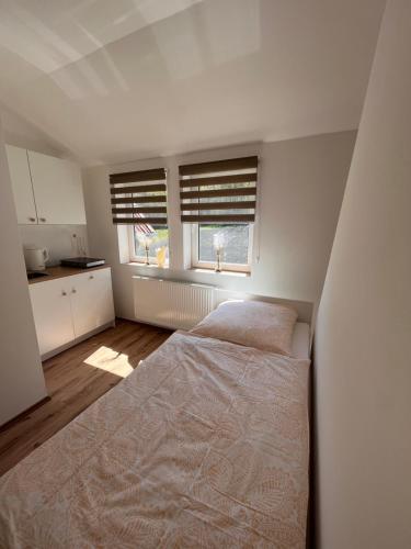 a white bedroom with a bed and a window at Apartment Södderich 1 in Waake