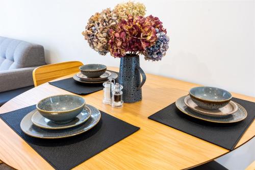 a table with four plates and a vase with flowers on it at Stylish home in Christchurch central in Christchurch