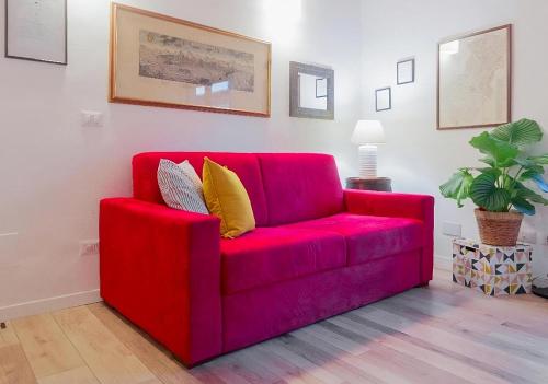 a red couch in a living room with a plant at CALIMARA18 25" from Florence AC SmartTV in Prato