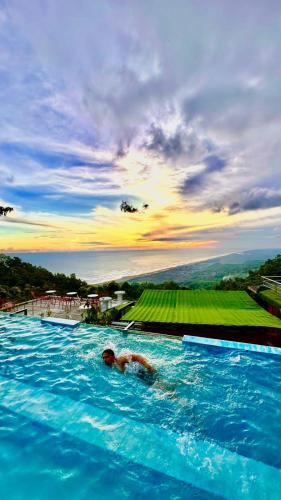 a person swimming in a large swimming pool at Glamping Omah Kayu at Watu Paris Jogja in Girijati