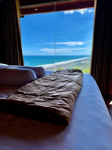 a bed in a room with a large window at Glamping Omah Kayu at Watu Paris Jogja in Girijati