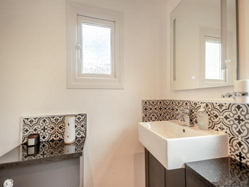 ein Badezimmer mit einem weißen Waschbecken und einem Spiegel in der Unterkunft Glanllyn in Betws-y-coed