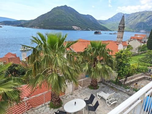 a balcony with palm trees and a view of the water at Forteca home in Perast