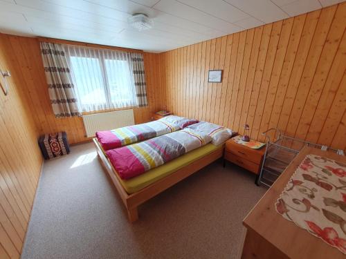 ein Schlafzimmer mit einem Bett und einer Holzwand in der Unterkunft Ferienstudio in Unterschächen in Unterschächen