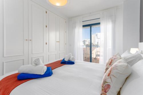 Un dormitorio blanco con una cama grande con dos animales de peluche. en Apartamento Marbella Playa Av Nabeul en Marbella