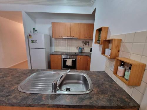 a kitchen with a sink and a white refrigerator at Little Monica Apartment- Spacious, Affordable & Central in Perth