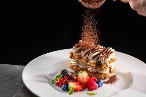 a piece of cake on a white plate with fruit at Lux Garden Hotel in Azuga
