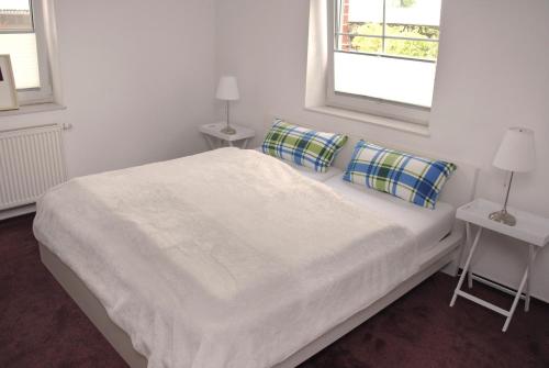 a bedroom with a white bed with two windows at Ferienwohnung Hof Konietzke in Thale