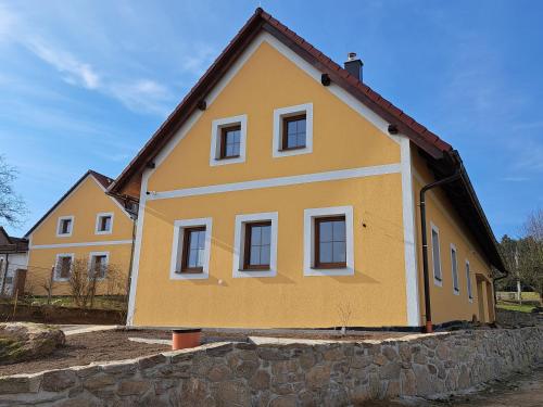 a yellow house with a stone wall at RYBÁŘSKÁ CHALUPA in Horní Stropnice