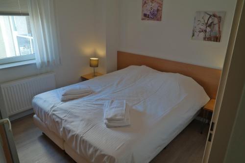 ein Schlafzimmer mit einem weißen Bett und Handtüchern darauf in der Unterkunft Seaside, Deurloo 53-07 in Cadzand