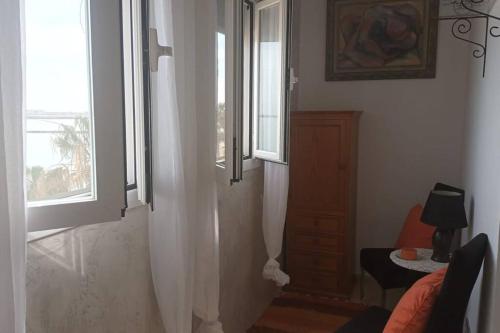 a living room with two windows and a chair at ApartPlaya (1ª Línea) in Melilla