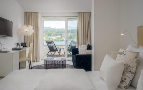 a bedroom with a bed and a living room at Seehotel Europa Resort in Velden am Wörthersee