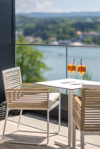 two glasses of wine sitting on a table on a balcony at Seehotel Europa Resort in Velden am Wörthersee
