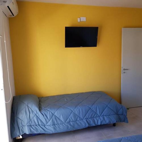 1 dormitorio con cama azul y pared amarilla en Dpto. San Luis Zona Shopping/centro en San Luis