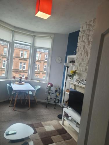 ein kleines Wohnzimmer mit einem Tisch und einem TV in der Unterkunft Tollcross Near Glasgow City Centre in Glasgow