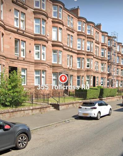 dois carros estacionados em frente a um grande edifício de tijolos em Tollcross Near Glasgow City Centre em Glasgow