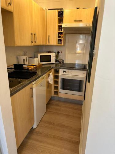 a kitchen with white appliances and wooden cabinets at double bedroom close to common park & city centre in Southampton